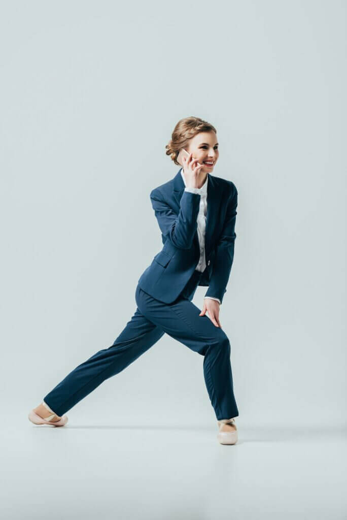 businesswoman in suit and ballet shoes talking on smartphone, isolated on grey